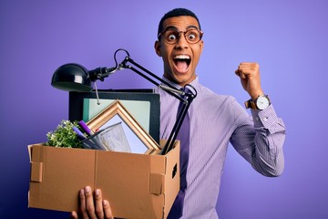 Handsome african american man fired holding box with work objects over purple background screaming proud and celebrating victory and success very excited, cheering emotion