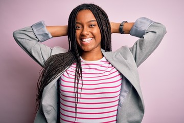 Canvas Print - Young african american business woman standing over pink isolated background relaxing and stretching, arms and hands behind head and neck smiling happy