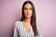 © Krakenimages.com - Young beautiful brunette woman wearing casual striped shirt over isolated pink background with serious expression on face. Simple and natural looking at the camera.