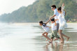 Smiling Young Asian happy family parents with child running and having fun together on the beach in summertime. Father, mother and kids relax and enjoy summer lifestyle travel holiday vacation.