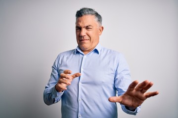 Poster - Middle age handsome grey-haired business man wearing elegant shirt over white background disgusted expression, displeased and fearful doing disgust face because aversion reaction. With hands raised