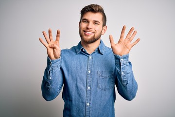 Young handsome blond man with beard and blue eyes wearing casual denim shirt showing and pointing up with fingers number nine while smiling confident and happy.