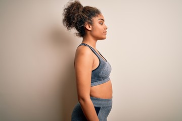 Young african american sportswoman doing sport wearing sportswear over white background looking to side, relax profile pose with natural face and confident smile.