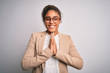 Sticker - Beautiful african american businesswoman wearing jacket and glasses over white background praying with hands together asking for forgiveness smiling confident.