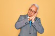 © Krakenimages.com - Middle age senior grey-haired handsome business man wearing glasses over yellow background sleeping tired dreaming and posing with hands together while smiling with closed eyes.