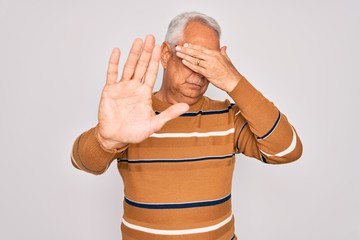 Poster - Middle age senior grey-haired handsome man wearing glasses and casual striped sweater covering eyes with hands and doing stop gesture with sad and fear expression. Embarrassed and negative concept.