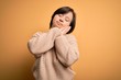 © Krakenimages.com - Young down syndrome woman wearing casual sweater over yellow background sleeping tired dreaming and posing with hands together while smiling with closed eyes.