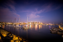 The Lights Of San Diego's Skyline Reflect Off The Waters Of The Pacific Ocean, With Sailboats In The Foreground.