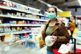 Fototapeta  - Woman with face mask making stock of toilet paper while buying in supermarket.