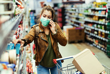 Woman With Face Mask Talking On The Phone While Shopping In Grocery Store.