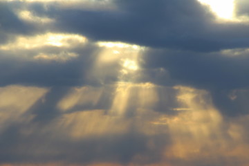 Wall Mural - the sun at sunset or dawn behind the clouds, shines through. the sun's rays in the sky.