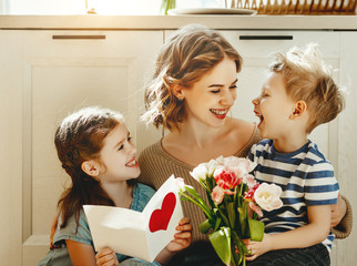 Wall Mural - cheerful little girl with card and youngest brother with bouquet of tulip flowers smiling and congra