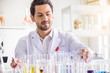 © totojang1977 - Attractive happiness scientist man lab technician assistant analyzing sample in test tube at laboratory. Medical, pharmaceutical and scientific research and development concept.