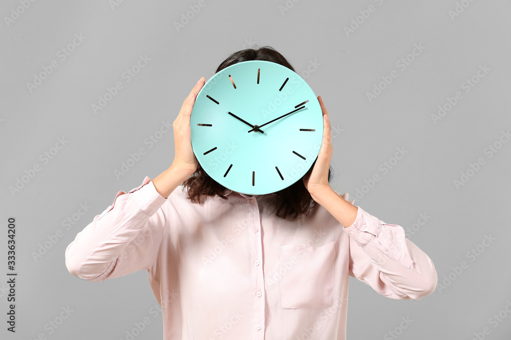 Businesswoman with clock on grey background. Time management concept