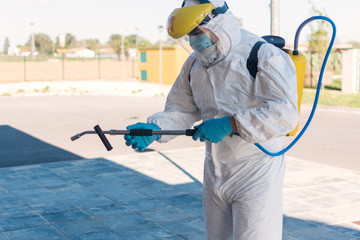 man wearing an nbc personal protective equipment (ppe) suit, gloves, mask, and face shield, cleaning