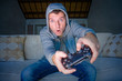 © TheVisualsYouNeed - indoors portrait of young excited and happy man at home playing videogames holding controller enjoying cheerful in video gaming addiction and technology geek concept