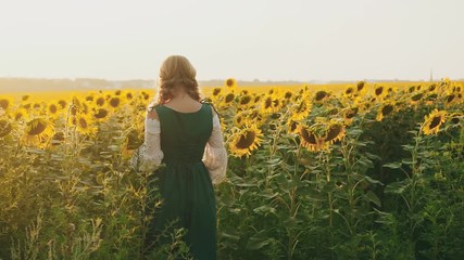 Wall Mural - Rural young woman turned away walking beautiful blooming sunflower field. Bouquet yellow flowers. National green costume white blouse. Medieval blonde enjoy summer nature. Backdrop blue sky sunlight