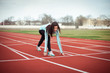 © Valeriia - A beautiful girl performs sports exercises in a blue stadium with brown rubber tracks. Woman in a blue trowel and black leggings.