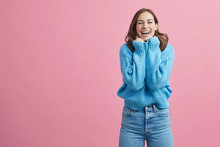 Portrait Of Happy And Lovely Young Woman In A Blue Winter Sweater On A Pink Background