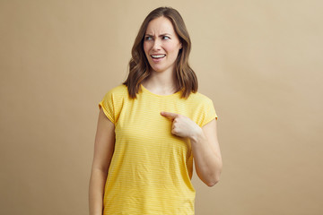 Wall Mural - Portrait of skeptical girl pointing at her self signaling that she is not going to be the one to do it