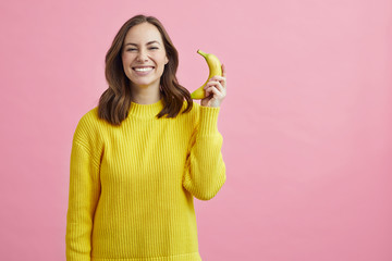 Wall Mural - Portrait of pretty girl pretending that the banana is a phone 