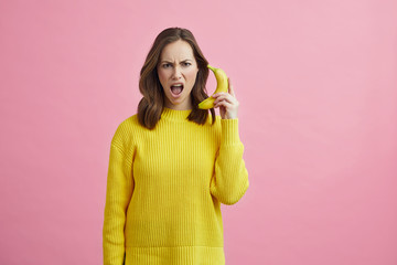 Wall Mural - Portrait of angry girl pretending that the banana is a phone 