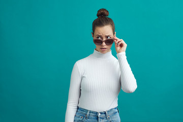 Wall Mural - Young woman looking over her sunglasses and looking at copy space 