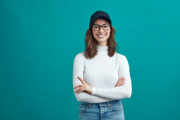 Portrait of young woman wearing glasses and cap looking like a creative person