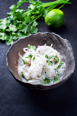 Wall Mural - Traditional Peruvian gourmet ceviche see bass filet piece with onion rings and coriander in lime juice as closeup in a modern design bowl