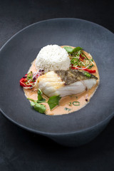 Wall Mural - Gourmet fried skrei cod fish Thai curry with jasmine rice and chili as closeup on a modern design plate with copy space