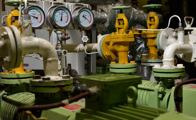 Engine room interior of a big ocean going ship with gauges, electrical motors, generators and piping