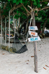 Wall Mural - pieces of wood with hand painted beach activities attached to tree stump in Pangkor Island, Perak State, Malaysia