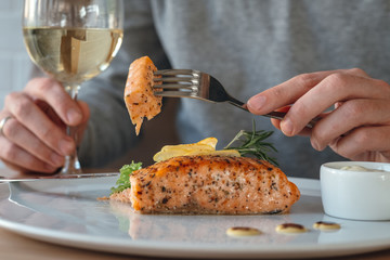 man eating salmon fish steak with fork an knife. crispy grilled salmon steak with lemon, salad and r