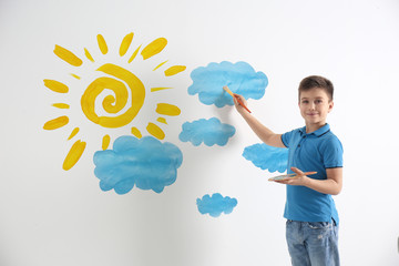 Sticker - Little boy drawing sun and clouds on white wall