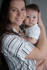 Wall Mural - Smiling mother holding her newborn baby daughter at home.