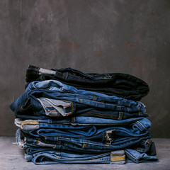 Wall Mural - Stack of jeans on a concrete background. Selvedge jeans. Copy space.