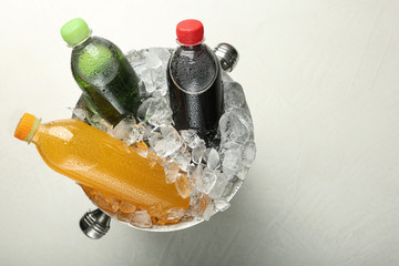 Wall Mural - Different soda drinks in metal bucket with ice on light grey table, top view