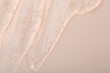 Pure transparent cosmetic gel on beige background, top view