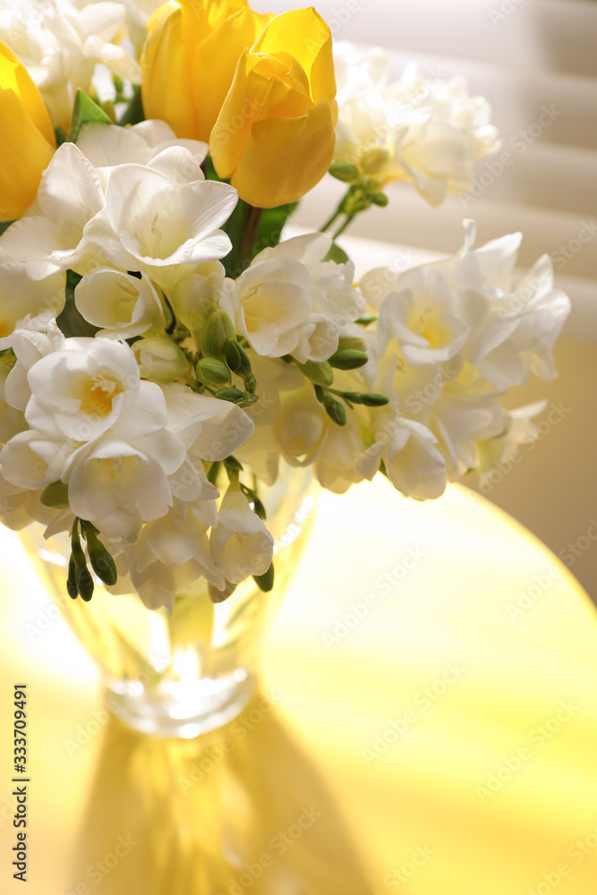 Beautiful bouquet with fresh freesia flowers in vase on table near window - obrazy, fototapety, plakaty 