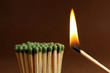 Burning match near unlit ones on brown background, closeup