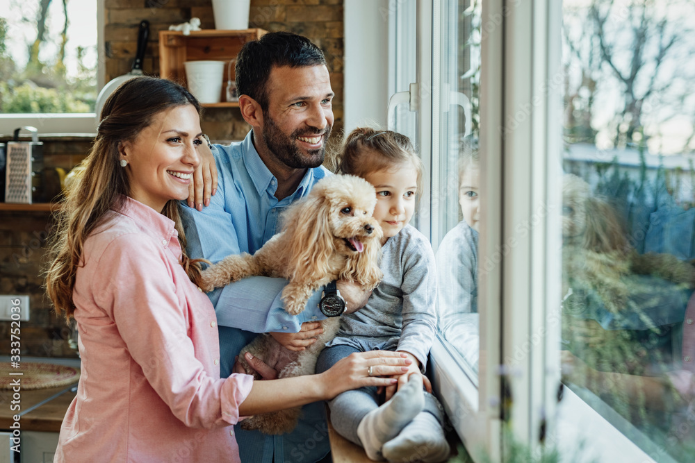 Happy family with a dog looking through the window at home.