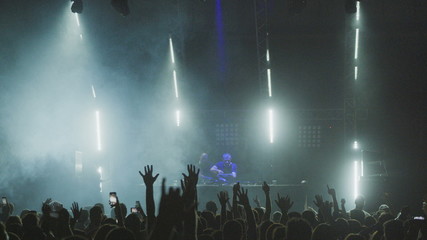 Silhouettes Crowd peoples are dance and listening a live music DJ in disco party hall. Behind crowd are DJ and disco spotlights  flashing lights stage. 