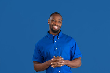 Wall Mural - Smiling, laughting. Monochrome portrait of young african-american man isolated on blue studio background. Beautiful male model. Human emotions, facial expression, sales, ad concept. Youth culture.