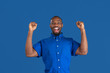 Crazy happy winner. Monochrome portrait of young african-american man isolated on blue studio background. Beautiful male model. Human emotions, facial expression, sales, ad concept. Youth culture.