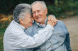 © prostooleh - Old couple in a park. Grandparents embracing. Woman in a blue shirt.