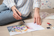 © New Africa - Woman painting flowers with watercolor on floor, closeup