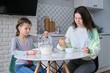 © Valerii Honcharuk - Girls having breakfast sitting at table in home kitchen