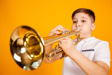 A Cheerful Boy Plays The Pipe Blowing His Cheeks. Humor Playing A Wind Instrument