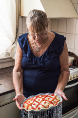 Wall Mural - older woman spends her days in quarantine cooking tuna potato salad and mayonnaise with bell peppers