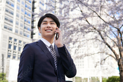 オフィス街の桜を背景にスマートフォンで電話する日本人男性ビジネスマン Foto De Stock Adobe Stock オフィス街の桜を背景にスマートフォンで電話する日本人男性ビジネスマン Foto De Stock Adobe Stock